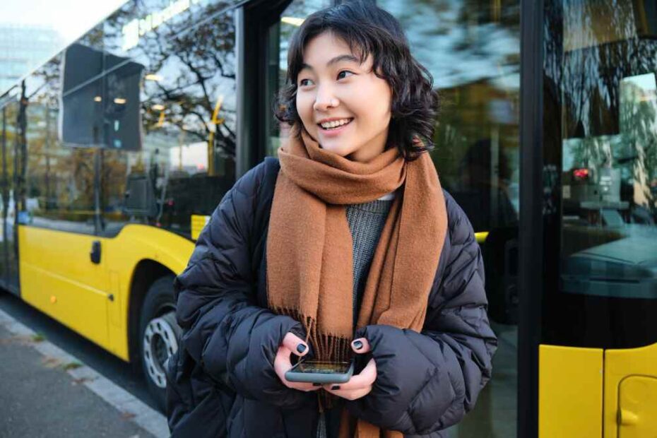 A young female passenger standing in front of a Bus.